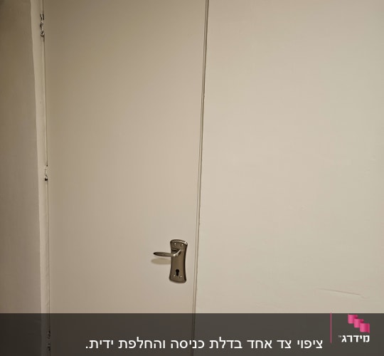 דלת לבנה עם ידית מתכת על קיר לבן